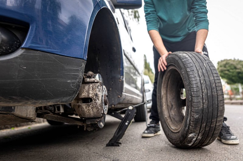Um homem muda um pneu danificado